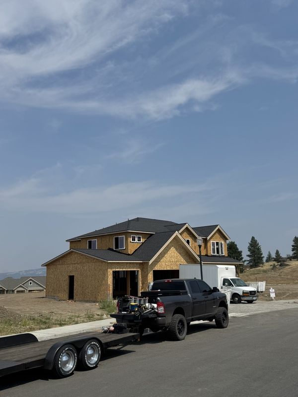 Newly installed charcoal architectural shingles viewed along the roof edge and gutter line